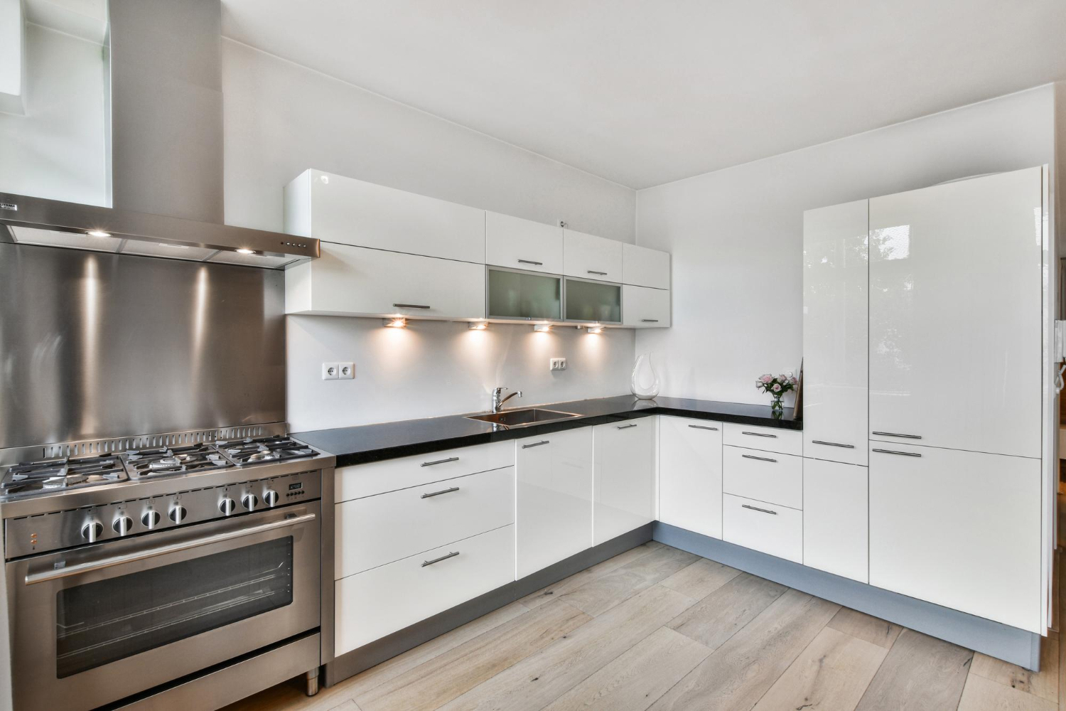 Stylish modular kitchen interior in Mangalore featuring white cabinets and wood floors.